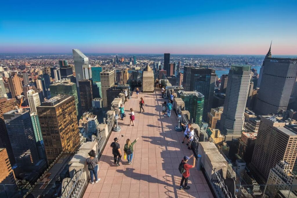 Top of the Rock view of the NYC skyline, tourists on the observation deck.